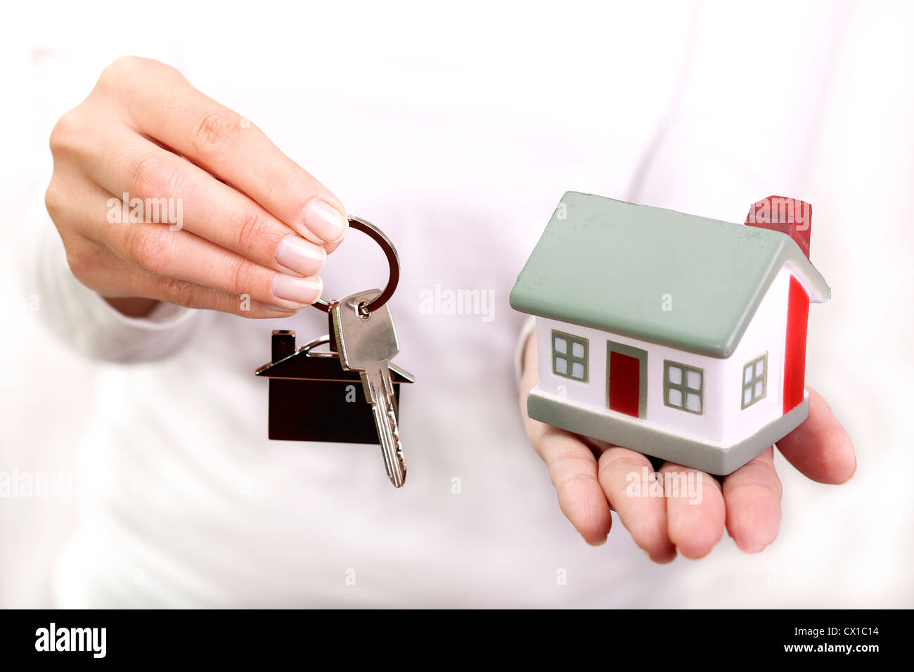 Miniature model house and keys resting on a female hand Stock Photo