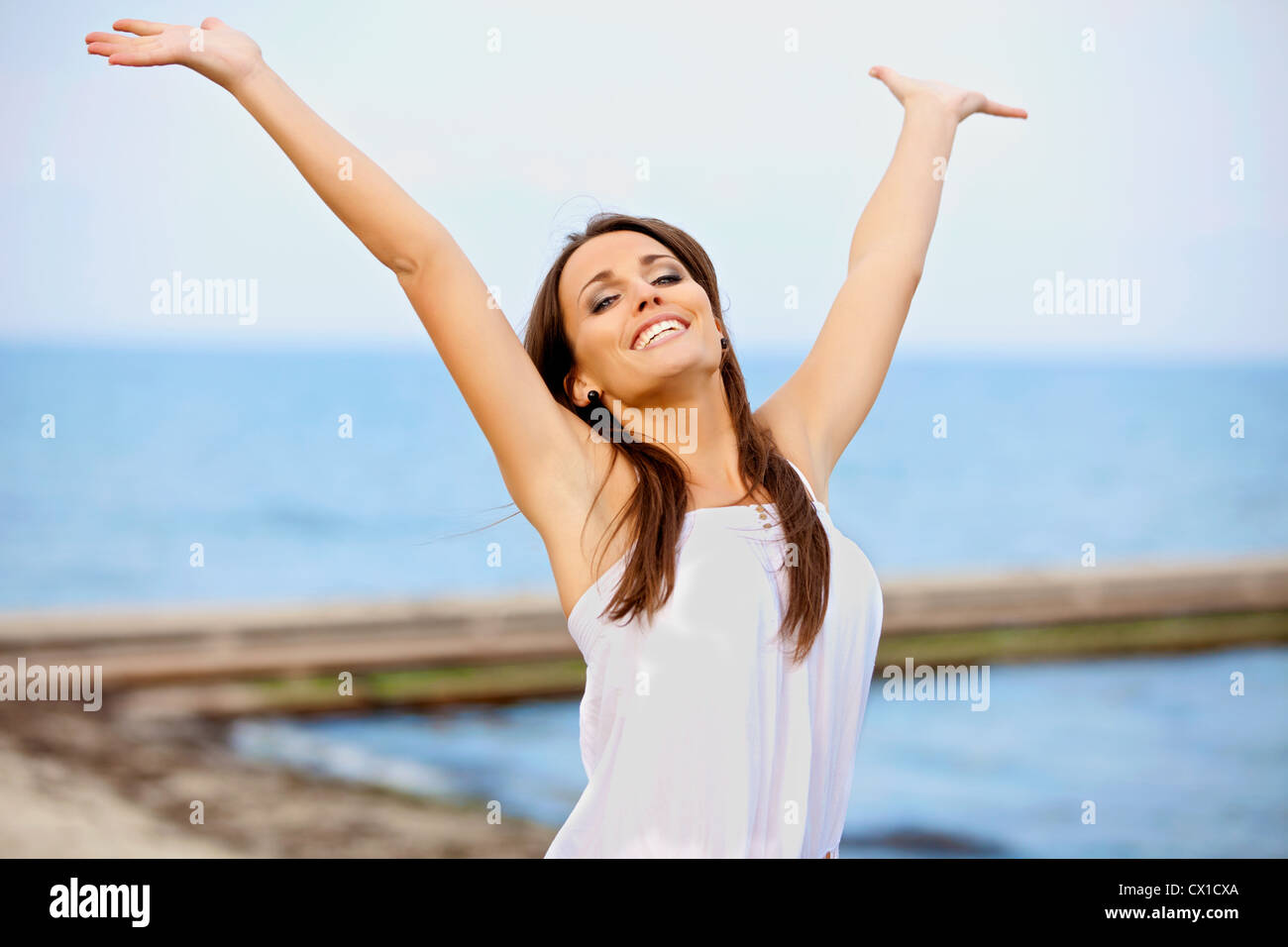 Portrait of a smiling happy woman raising her arms on the beach Stock ...