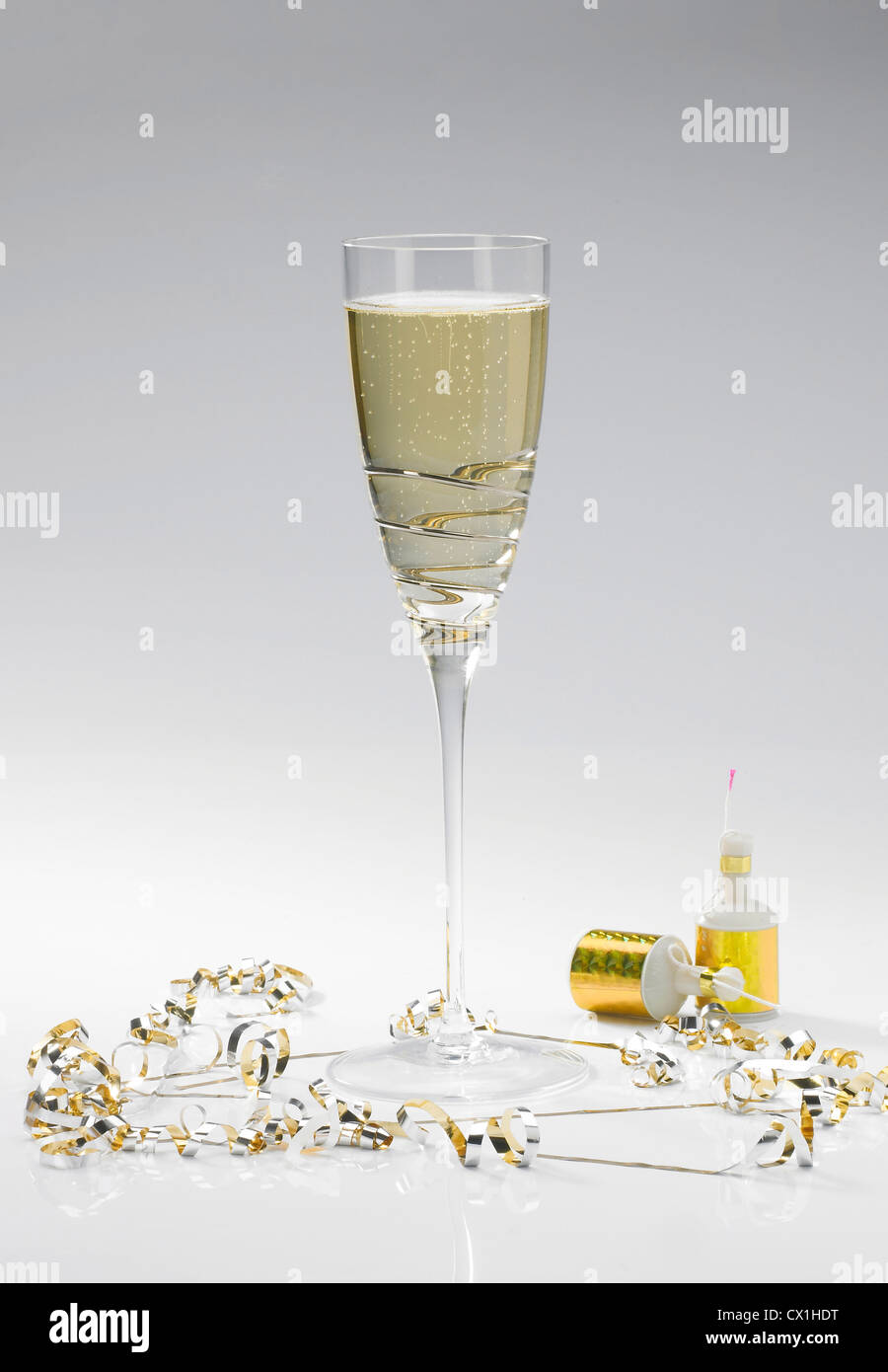 A single champagne flute on a white background with two party poppers and streamers Stock Photo
