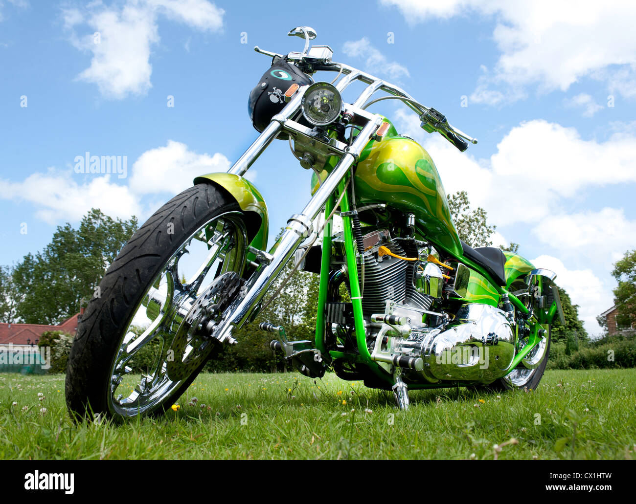Seen from below a custom painted chopper motorcycle on grass and with chrome finished engine Stock Photo