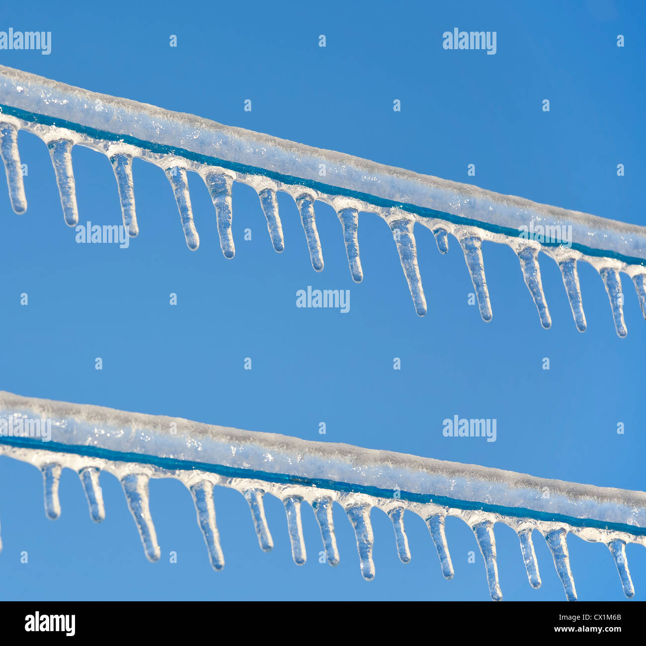 Icicles hanging from a frozen clothesline against a bright clear blue sky. Stock Photo