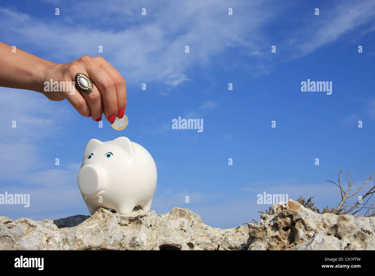A woman hand putting a euro coin on a piggy bank Stock Photo - Alamy