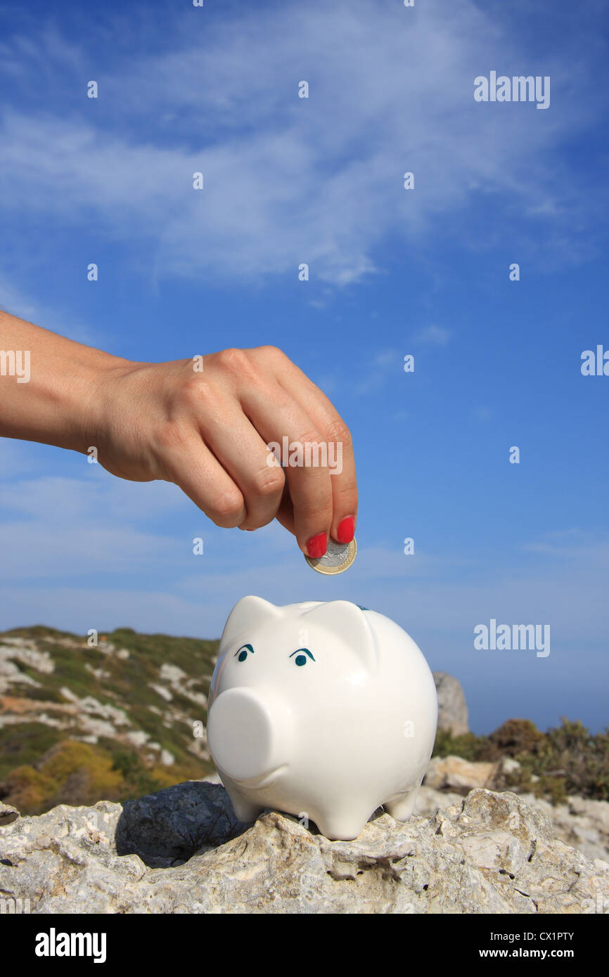 A woman hand putting a euro coin on a piggy bank Stock Photo - Alamy