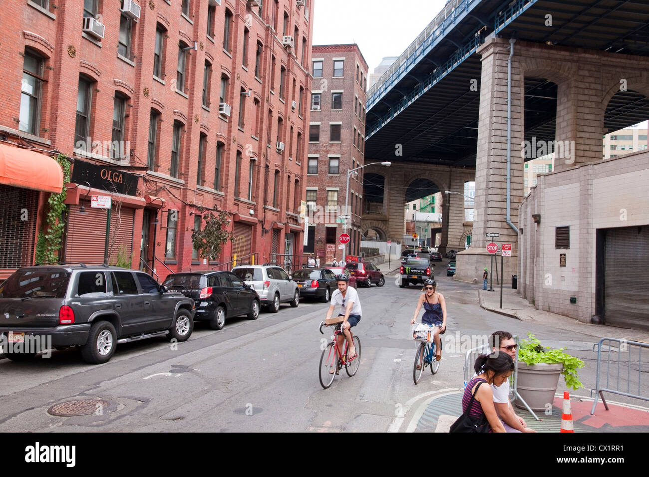 Bicyclists riding on Pearl Street beneath the Manhattan Bridge Overpass. Stock Photo