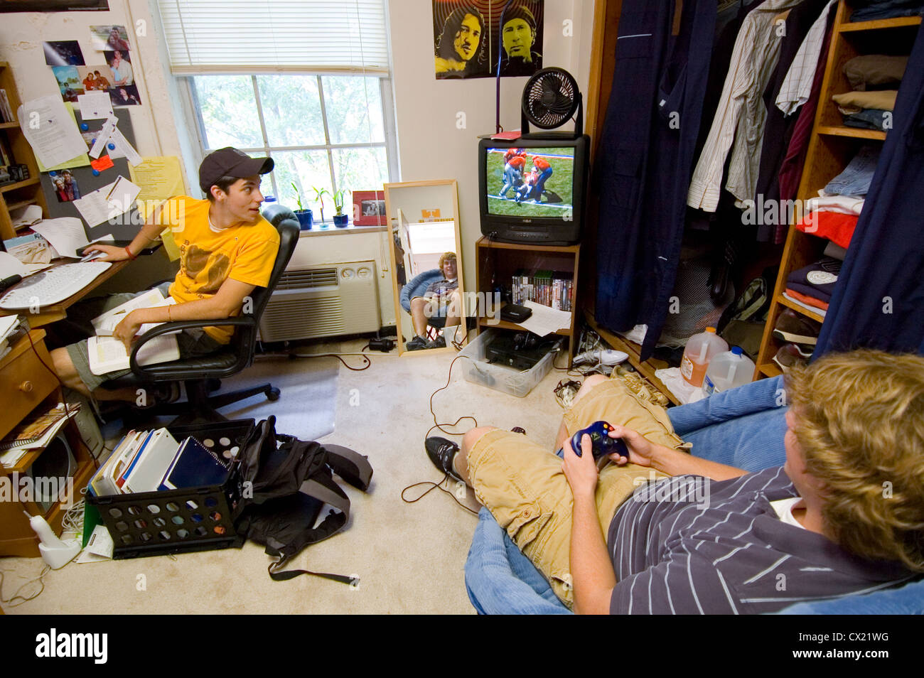 Two young male college students play a video game in their dorm room. Stock Photo