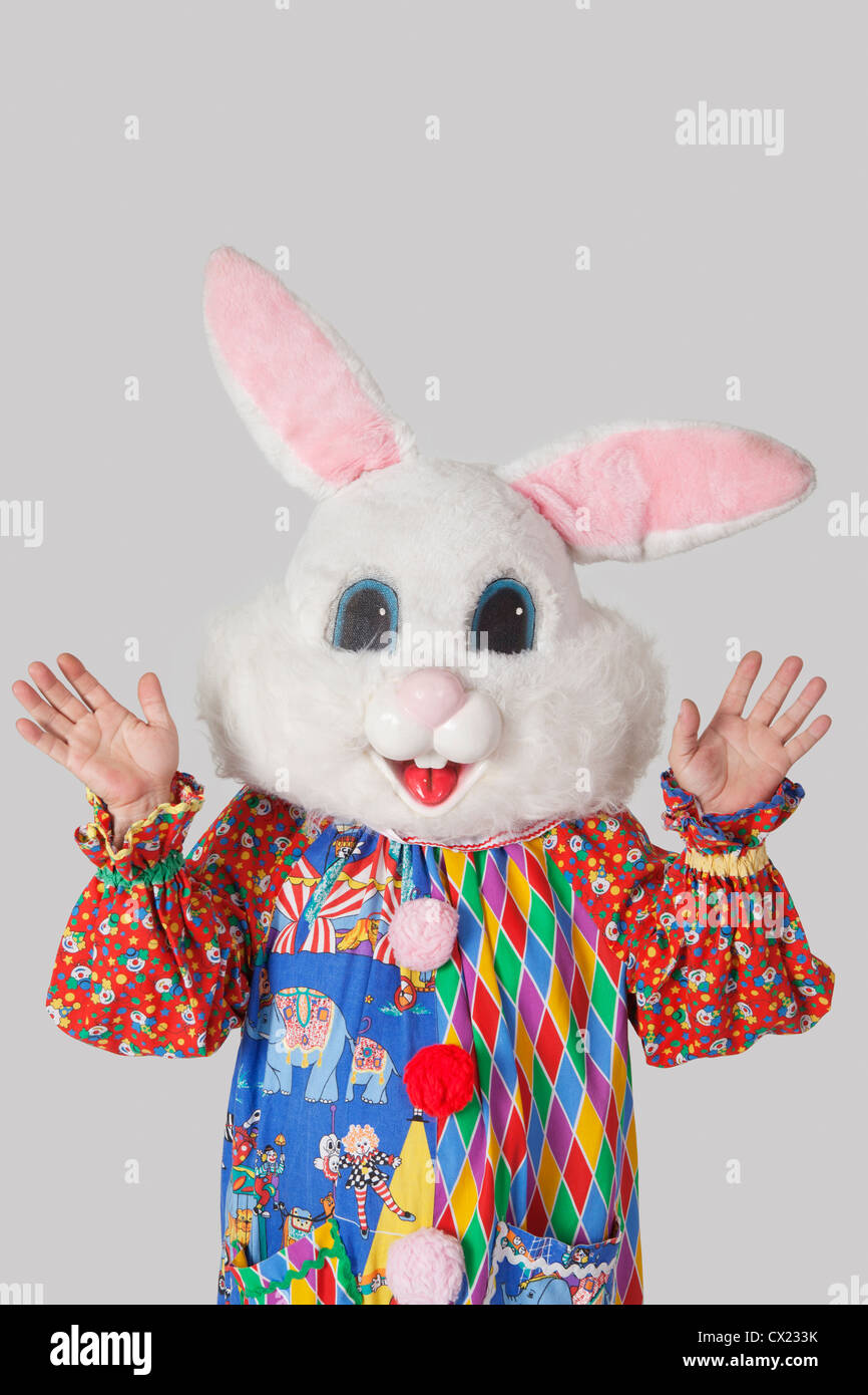 Man wearing bunny mask with standing raised hands against gray background Stock Photo