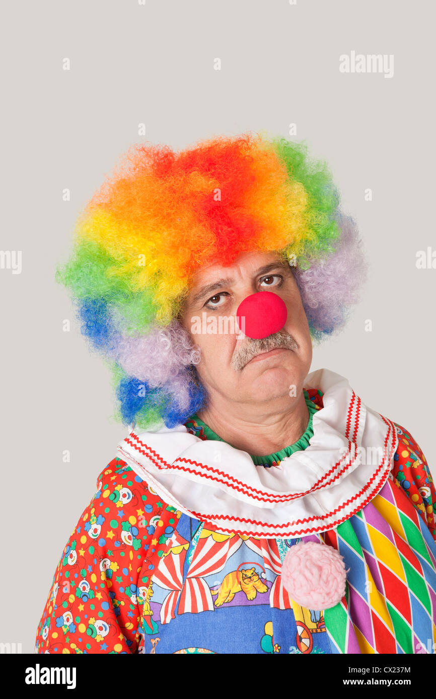 Portrait of sad senior male clown against colored background Stock Photo