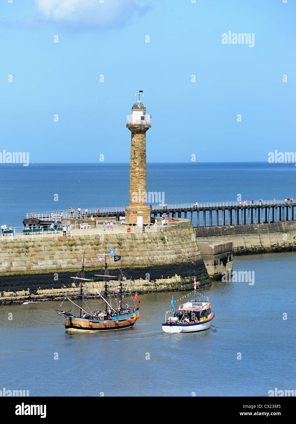 whitby lighthouse and boat trips passing each other england uk Stock Photo