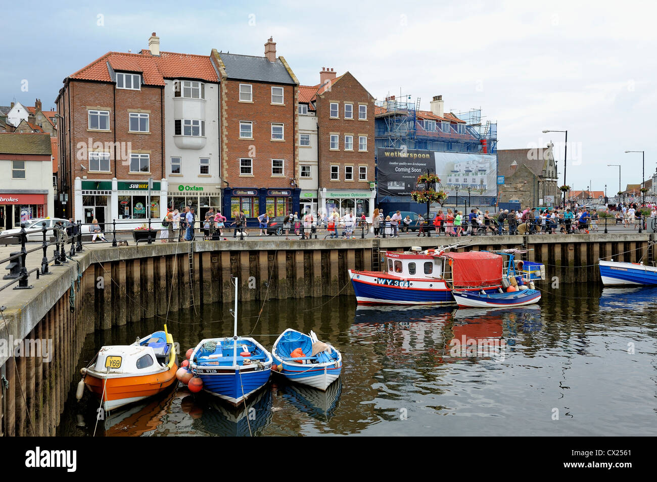 holiday makers in whitby harbour crabbing over the wall north yorkshire england uk Stock Photo