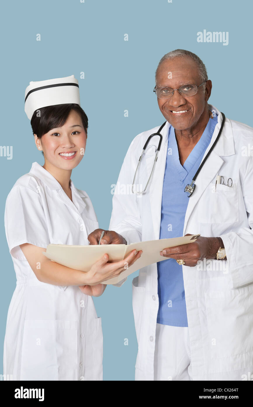 Portrait of happy medical professionals with medical report against light blue background Stock Photo