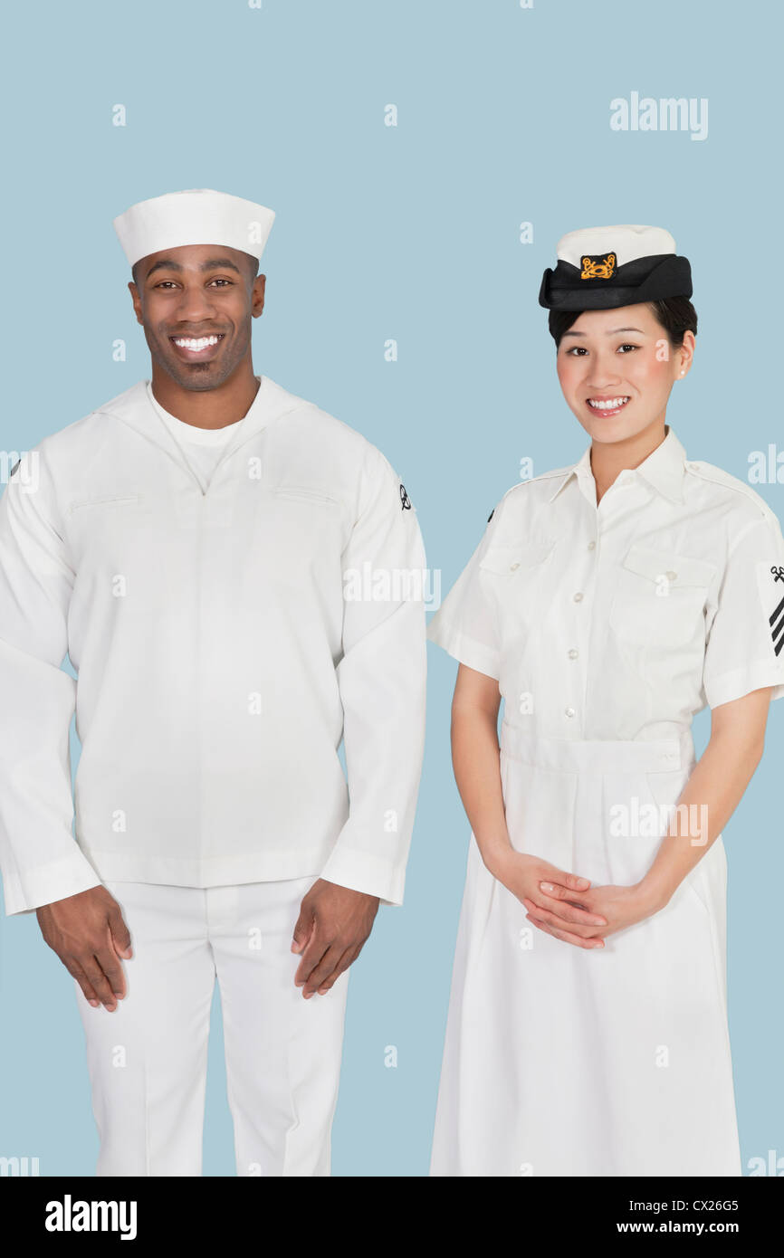 Portrait of happy female US Navy officer with male sailor over light blue background Stock Photo