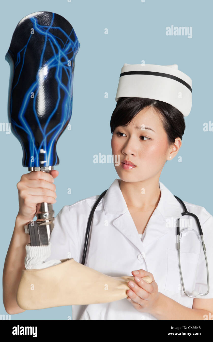 Female doctor looking at prosthesis foot over light blue background Stock Photo