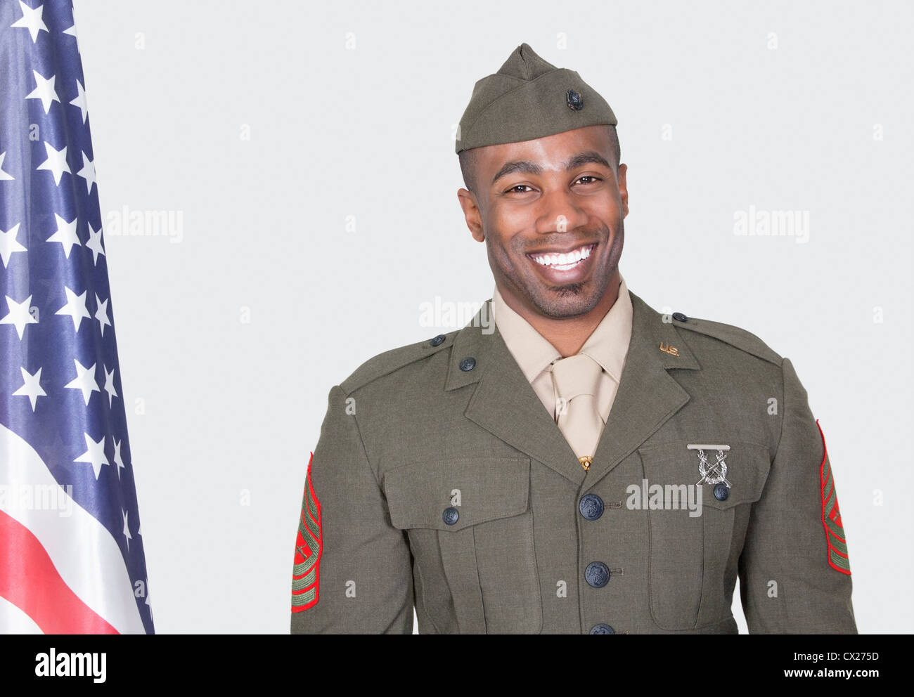 Portrait of a male US soldier smiling with American flag over gray ...