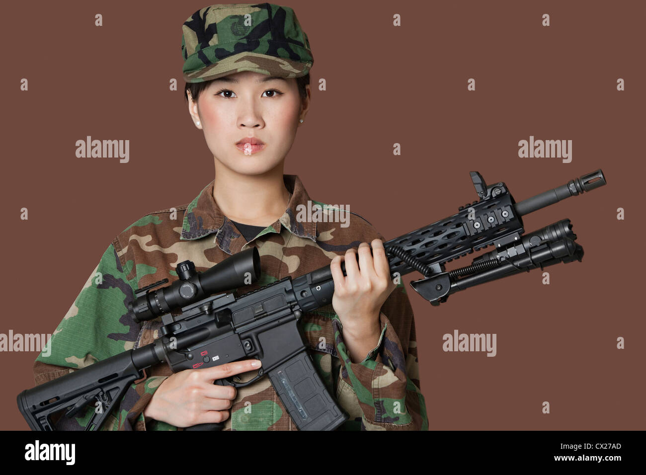 Portrait of beautiful young US Marine Corps soldier with M4 assault rifle over brown background Stock Photo