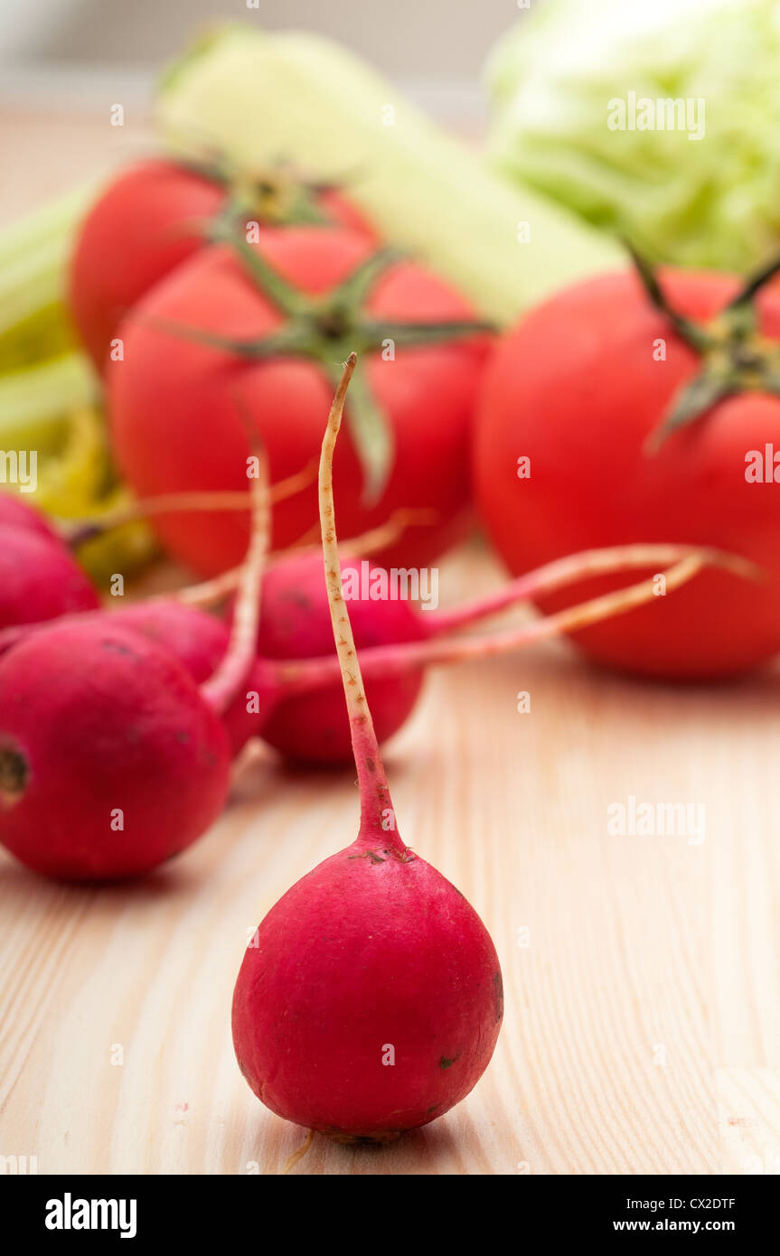 fresh raddish and vegetables over pine wood table closeup Stock Photo