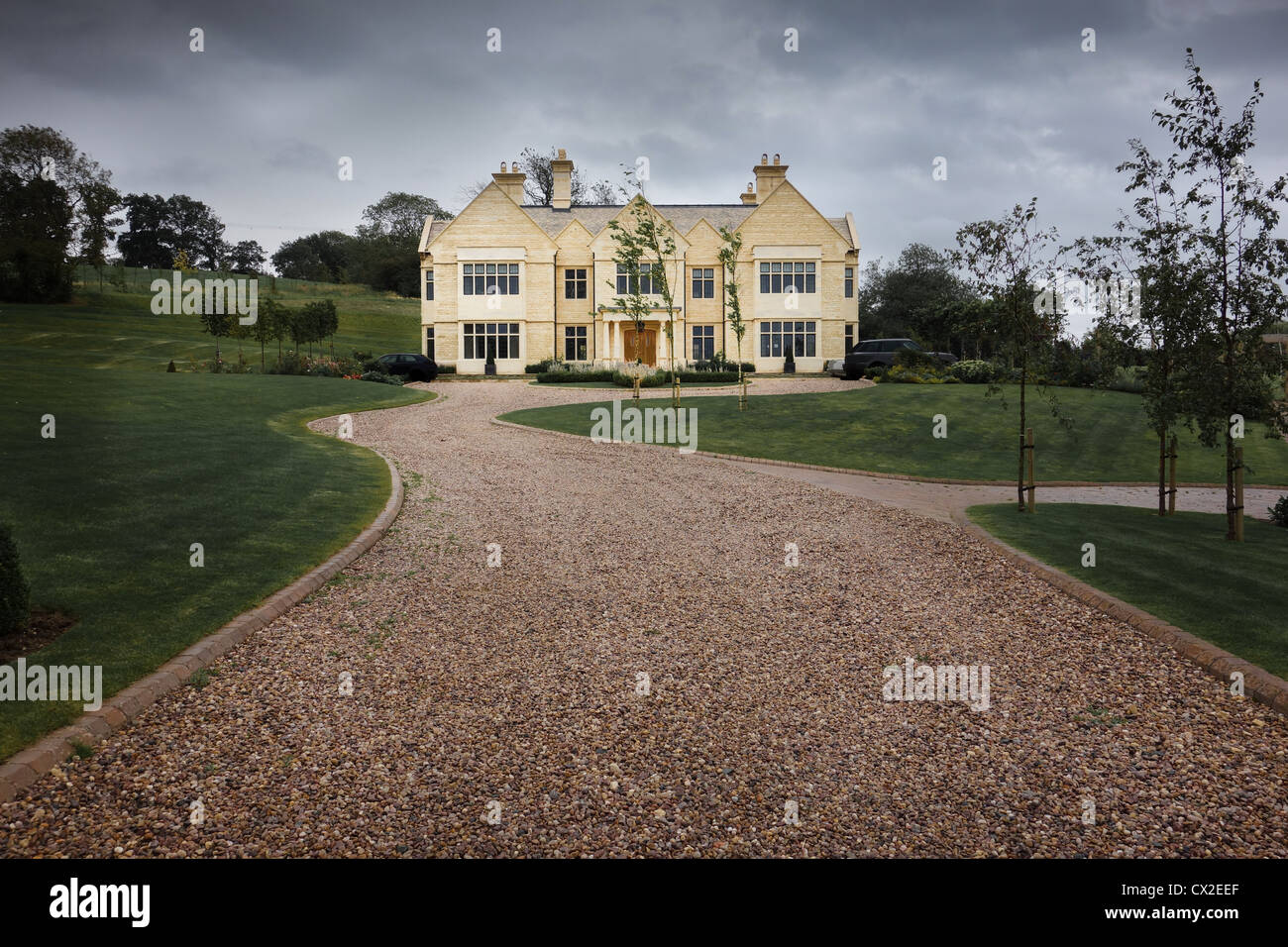 Pebble driveway to a modern stone country home in large grounds. Stock Photo
