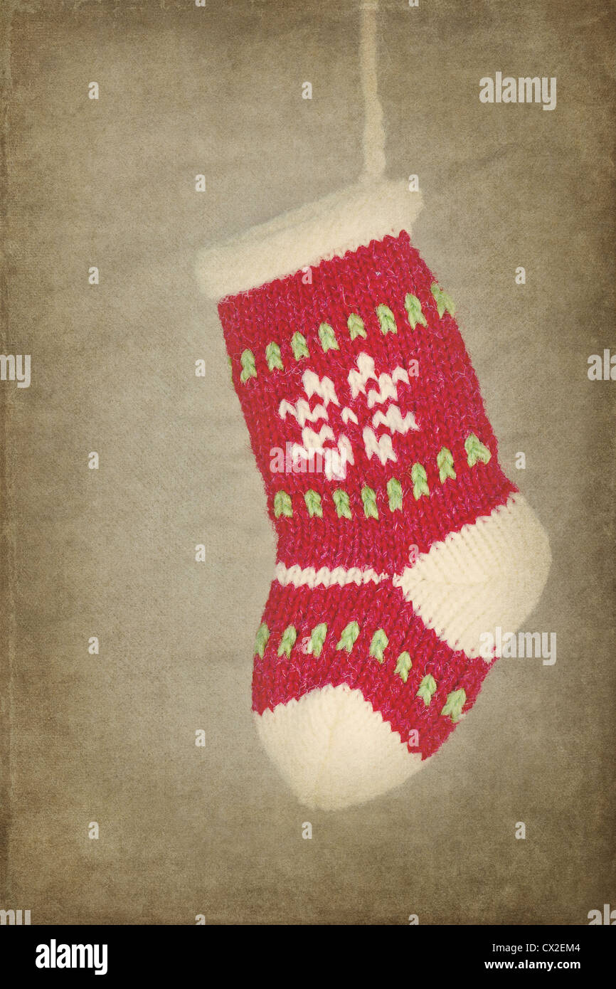 Red cute knitted Christmas sock / stocking hanging on rustic vintage textured background Stock Photo