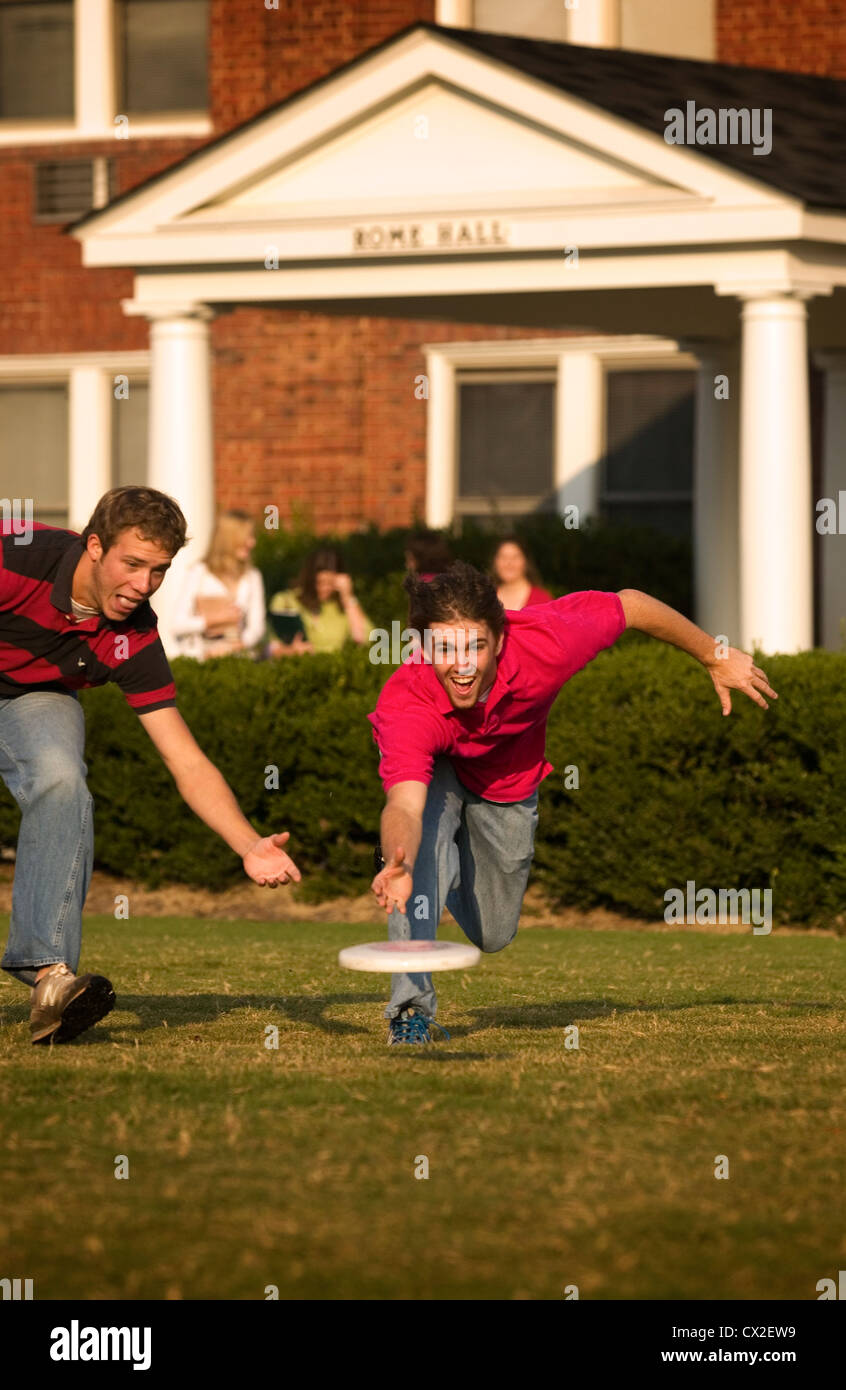 Two college boys play frisbee outside of their residence hall. Stock Photo