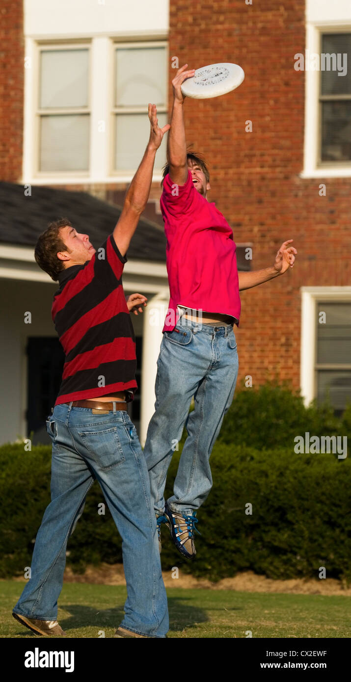 Two college boys play frisbee outside of their residence hall. Stock Photo