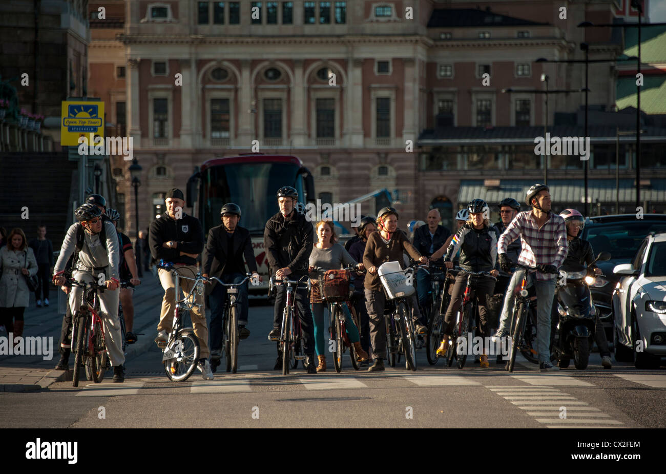 Commuters on bicycles waiting for green light in Gamla Stan Old Town in Stockholm Sweden with the Opera in the background Stock Photo