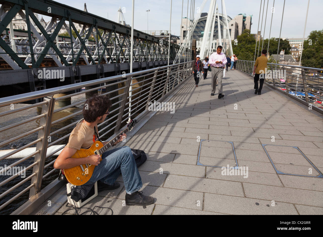 Busker playing electric guitar on the Golden Jubilee pedestrian Bridge
