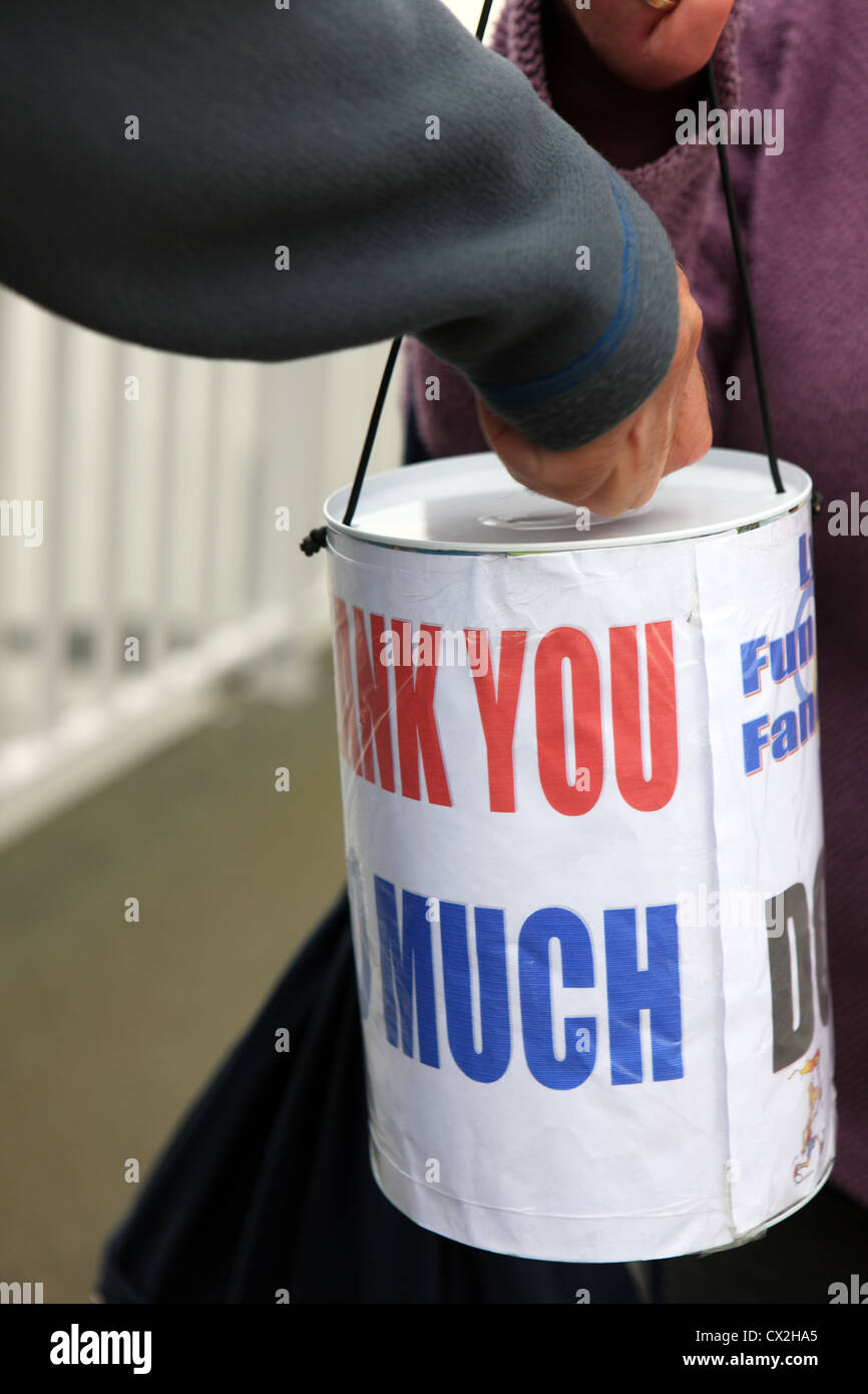 Charity collecting tin with a hand putting some money in and the words thank you so much written on it Stock Photo