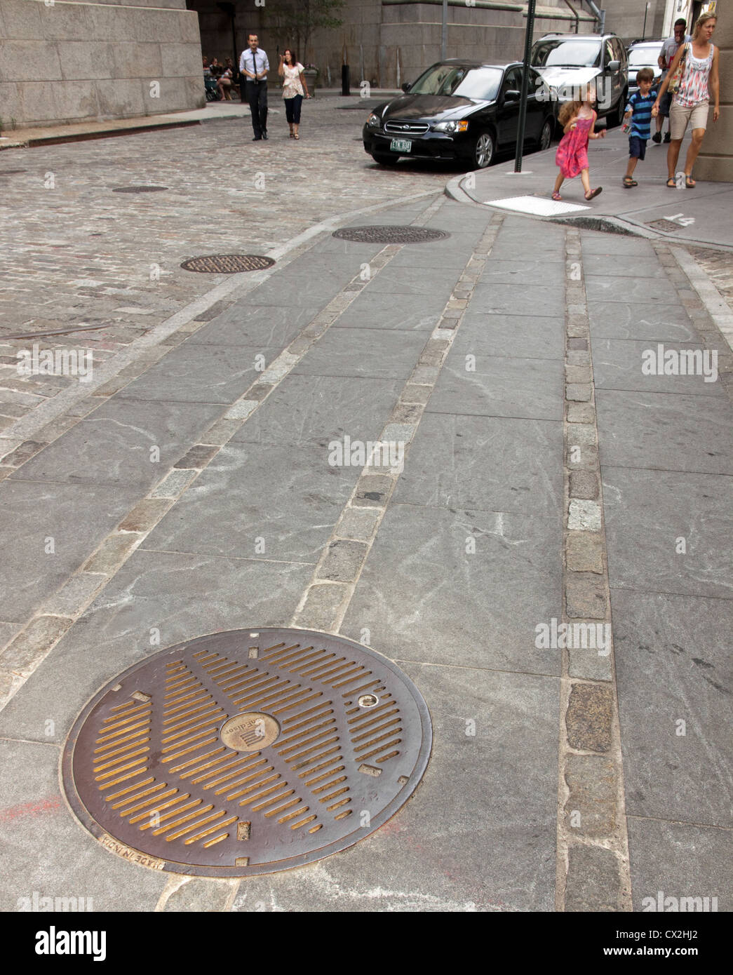 People walking the streets of DUMBO, Brooklyn, New York, nearby a manhole cover. Stock Photo