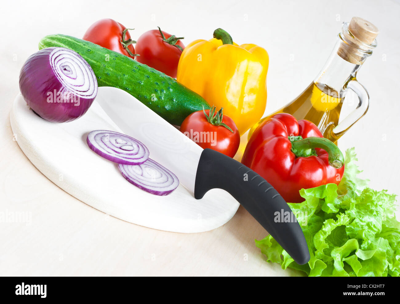 White ceramic knife, olive oil bottle, yellow pepper. sliced onion