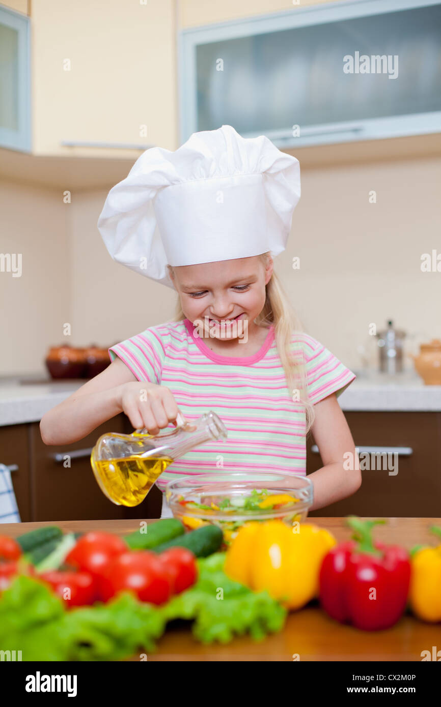 Little girl with oil preparing healthy food on kitchen Stock Photo