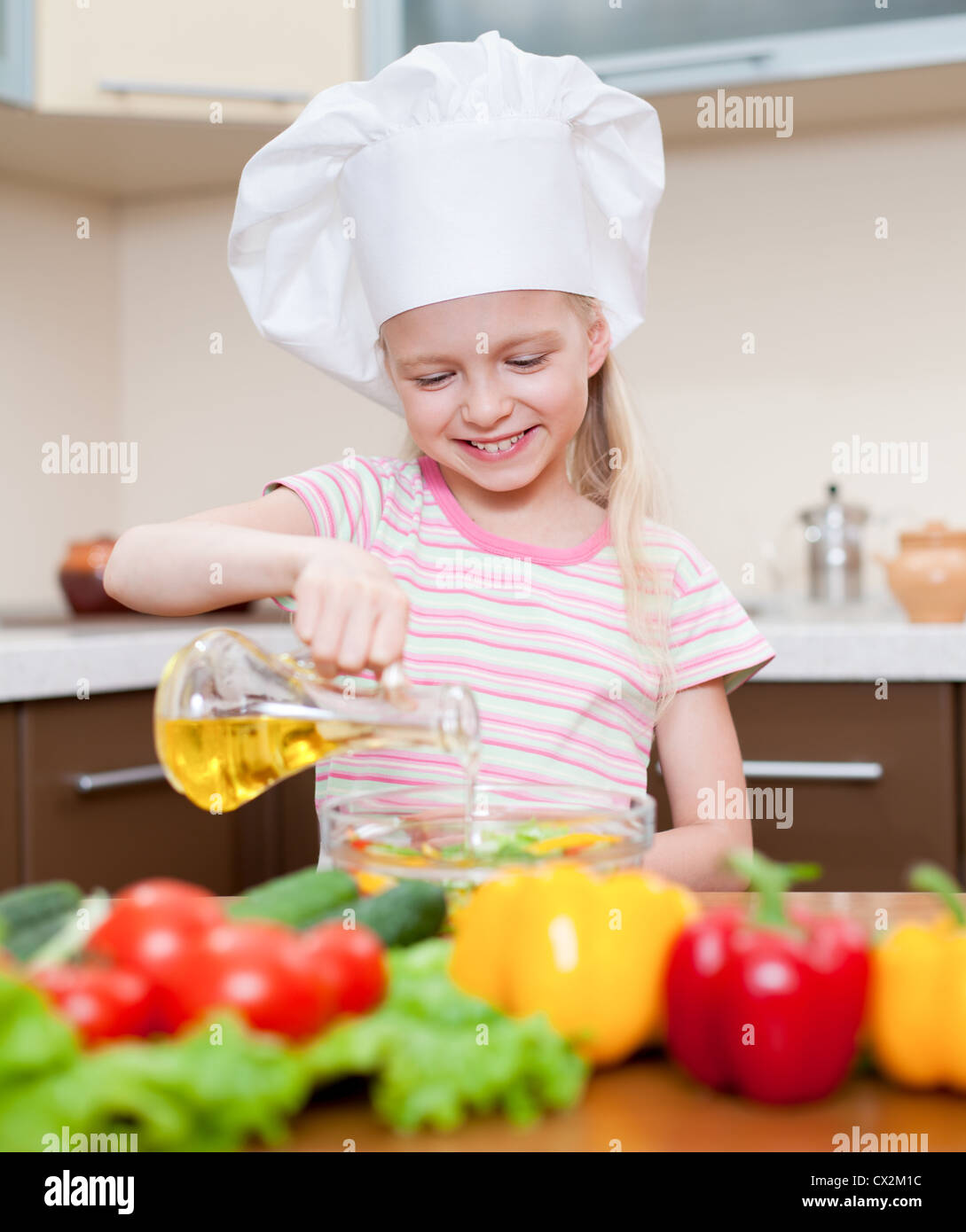 Little girl with oil preparing healthy food on kitchen Stock Photo