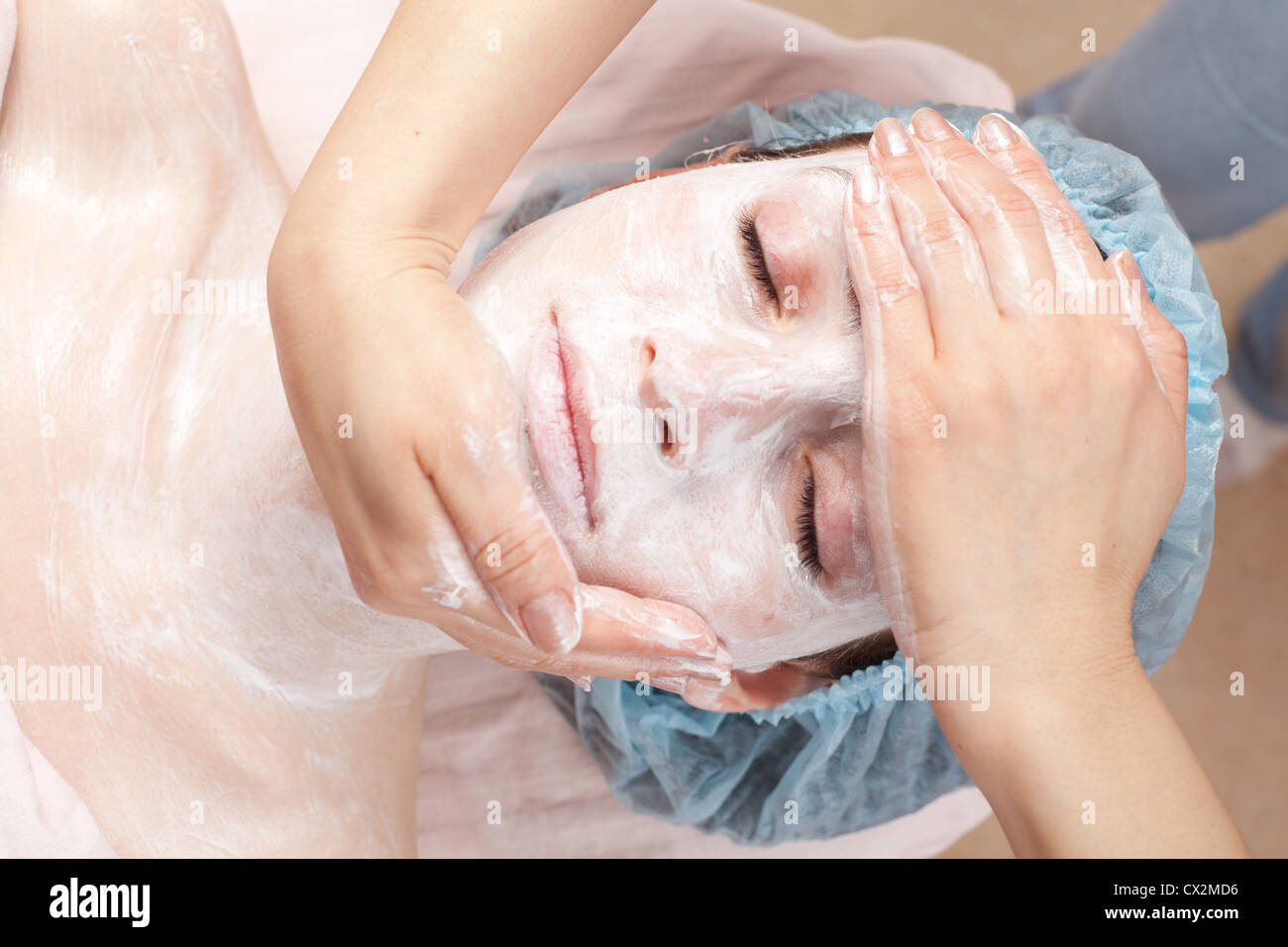 Beautiful woman with facial mask getting beauty treatment at salon Stock Photo