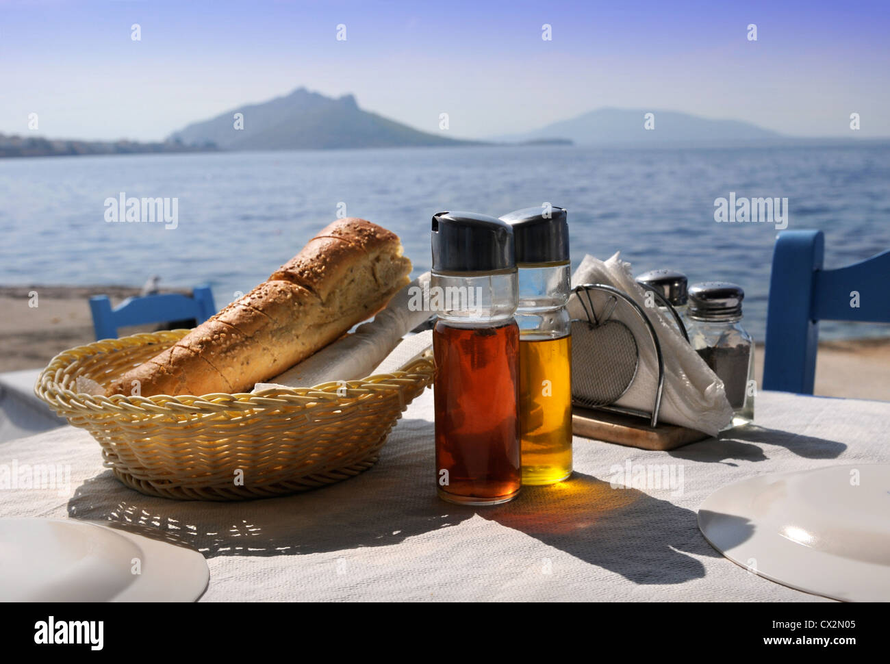 A table laid for a meal at a Greek taverna with bread and bottles of oil and vinegar Stock Photo