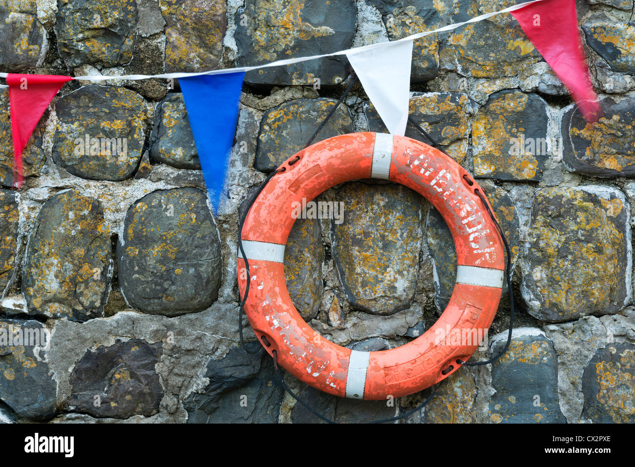 Life ring and bunting on the old harbour wall at Clovelly, Devon, England. Summer (August) 2012. Stock Photo