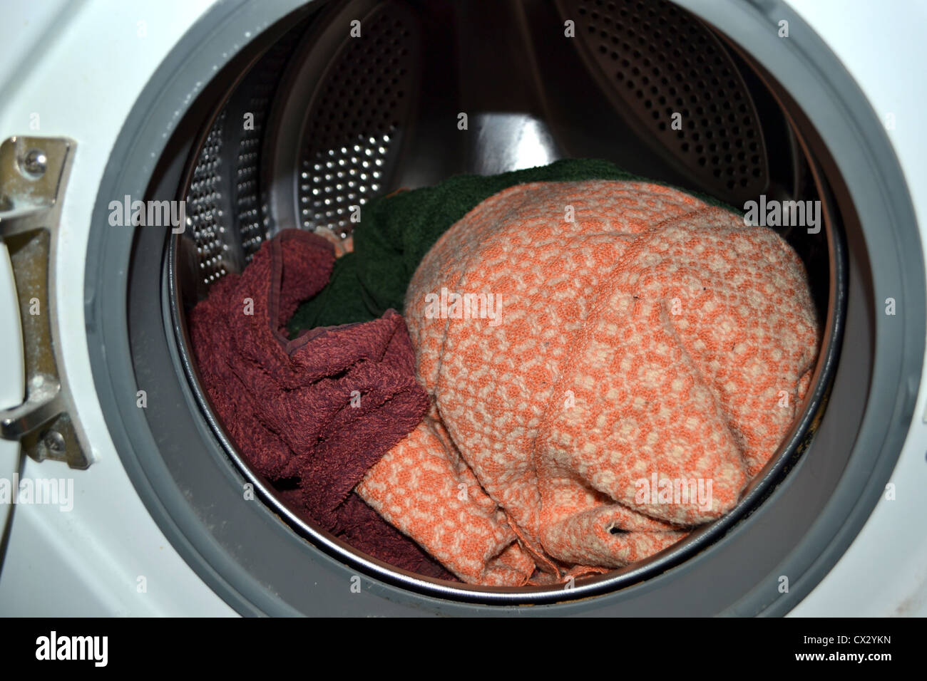 Inside a front loader washing machine filled with a few towels and