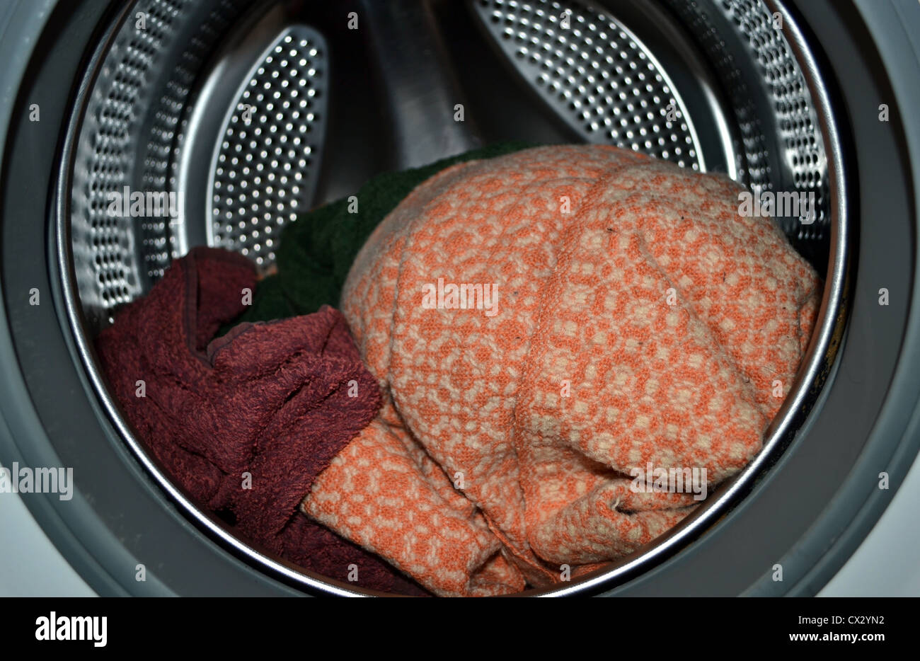 Inside a front loader washing machine filled with a few towels and