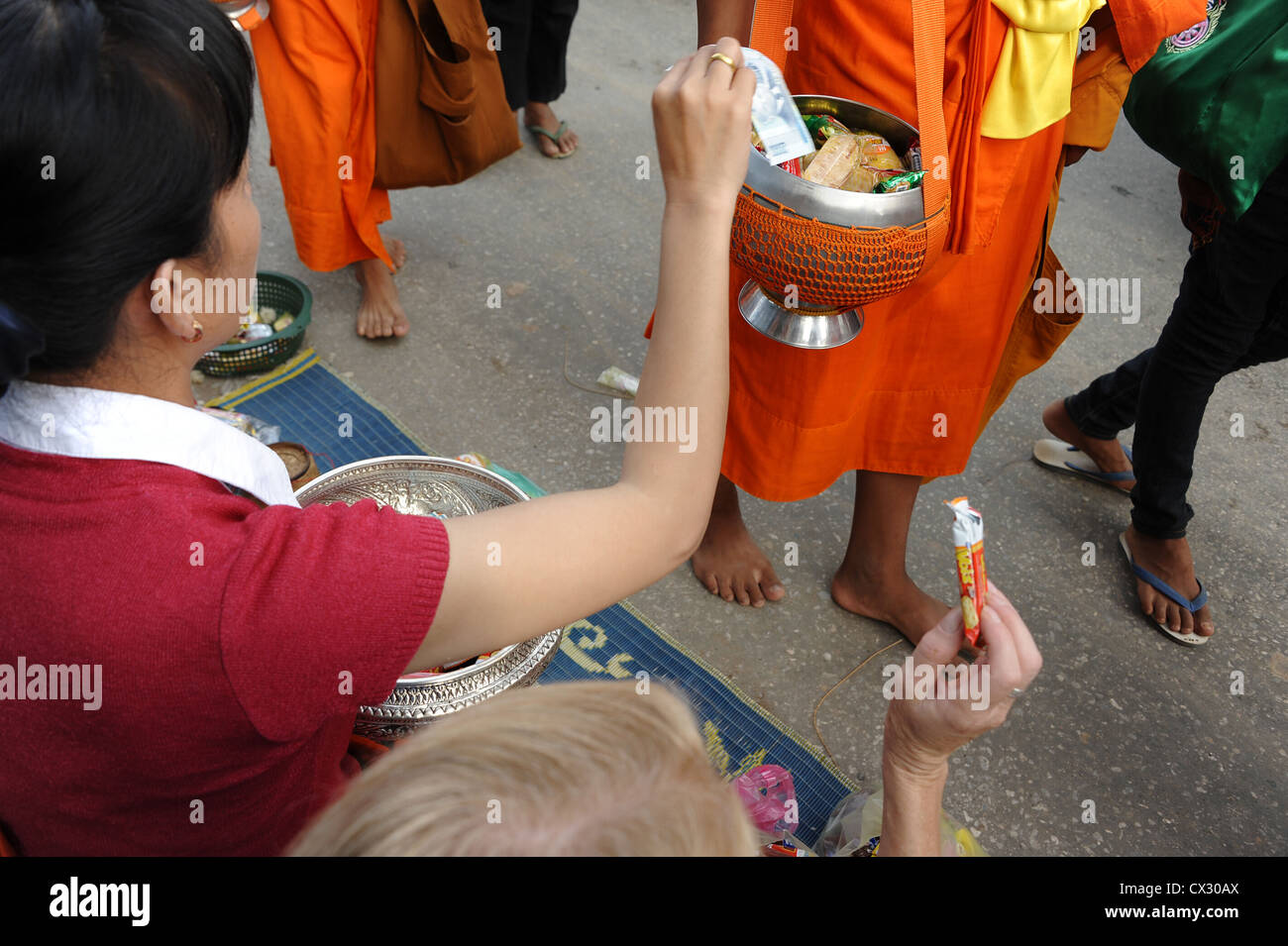 Villager puts money into monk's pot during Lent. Luang Prabang, Laos. Stock Photo