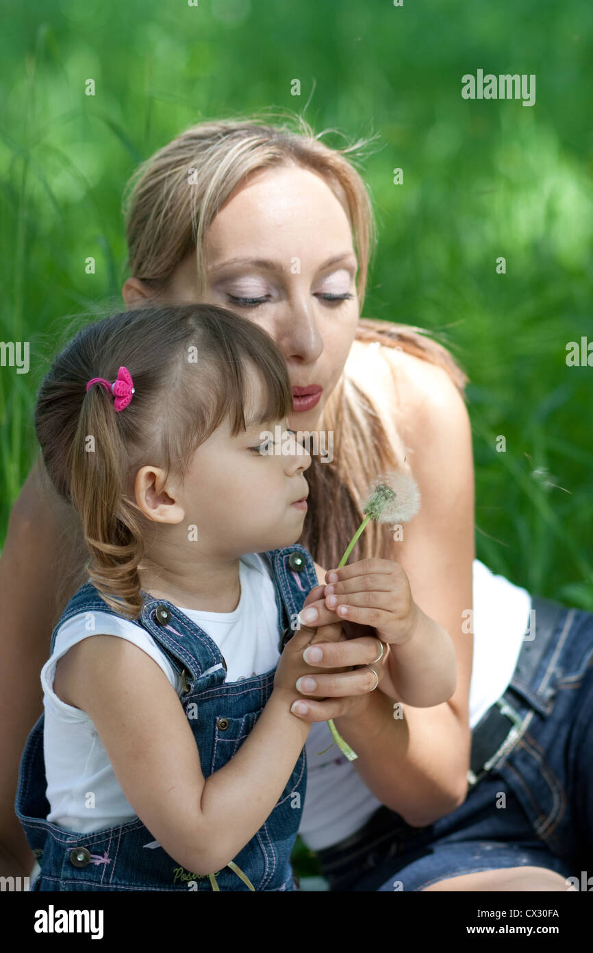 Mother and daughter in jeans with dandelion outdoor Stock Photo