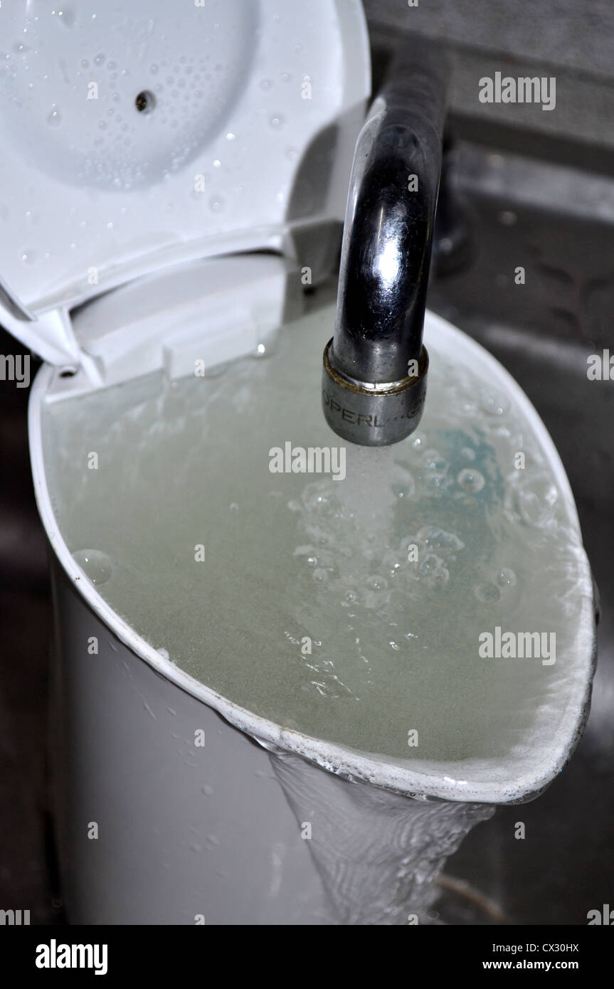 overflowing with water kettle / jug under tap / faucet Stock Photo