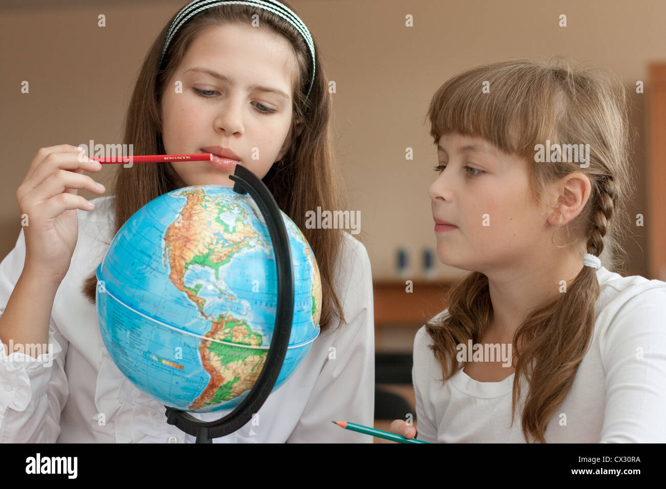 Two schoolgirls search geographical location using globe Stock Photo