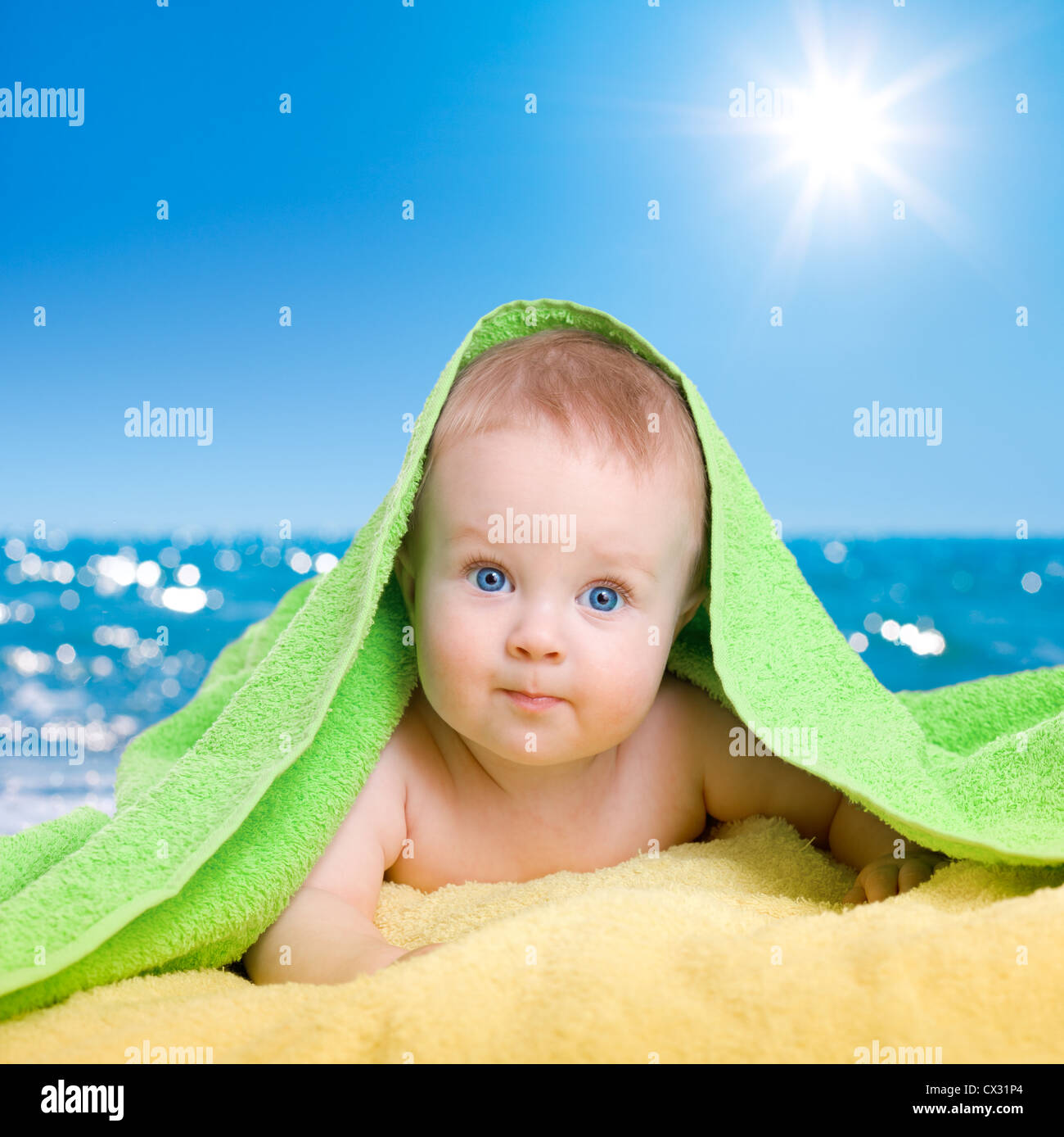 Adorable baby in colorful towel on sea beach Stock Photo
