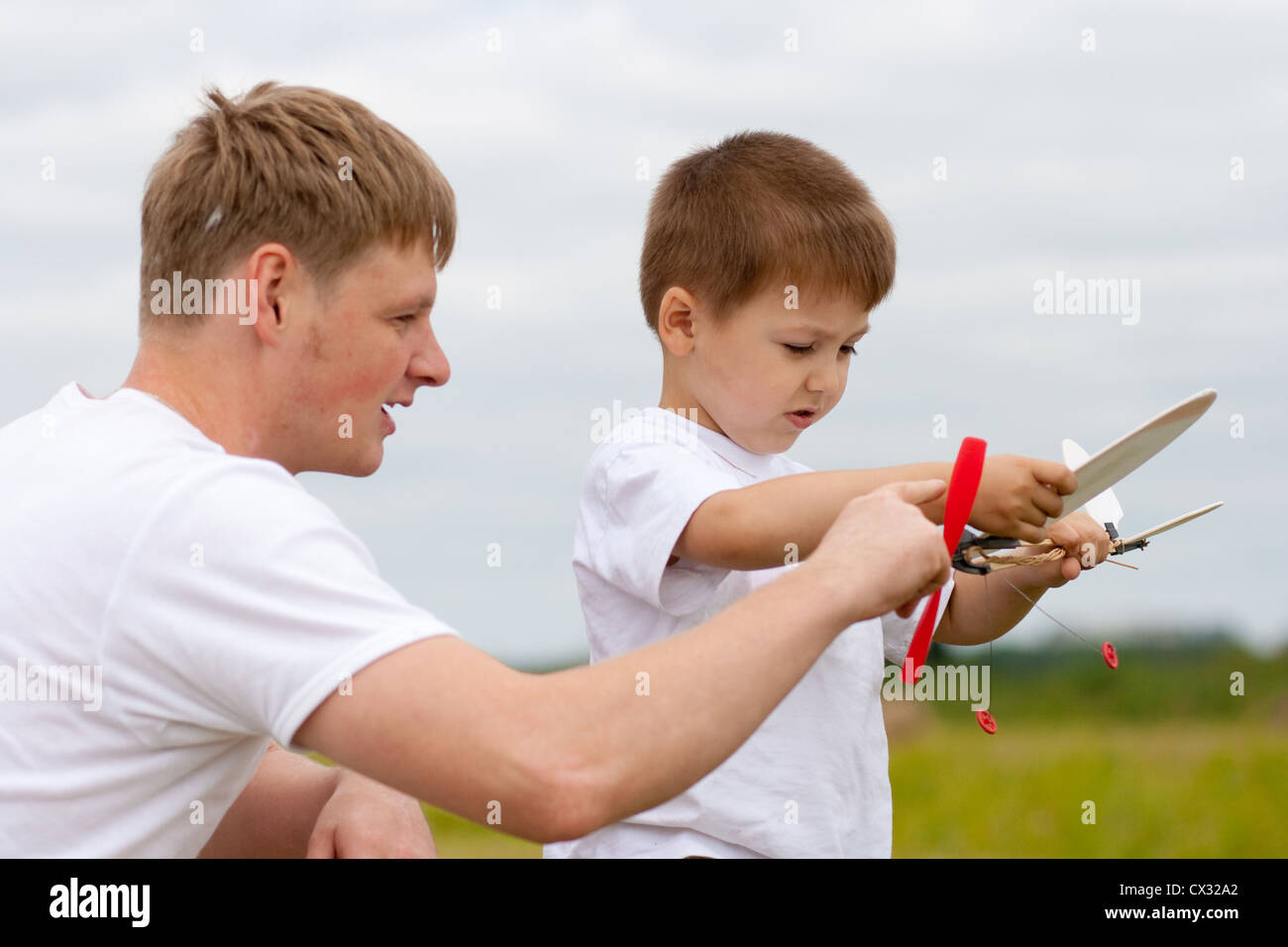 Father and son have fun with toy aircraft model in park Stock Photo