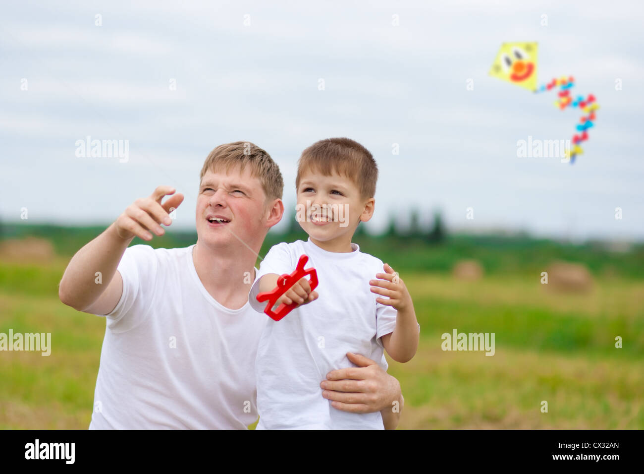 Father and son fly a kite together in summer field Stock Photo