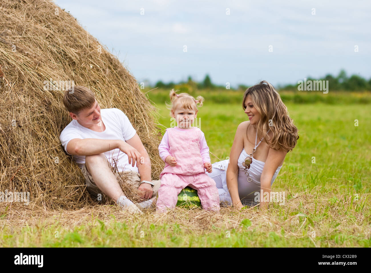 happy family sitting near haystack Stock Photo