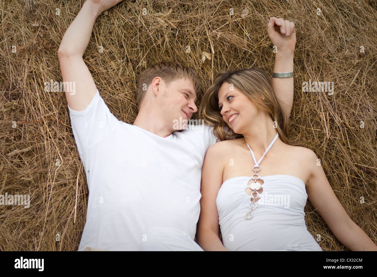 Happy young couple lying together in haystack Stock Photo
