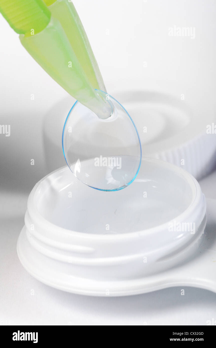 Contact lens in tweezers with white container Stock Photo