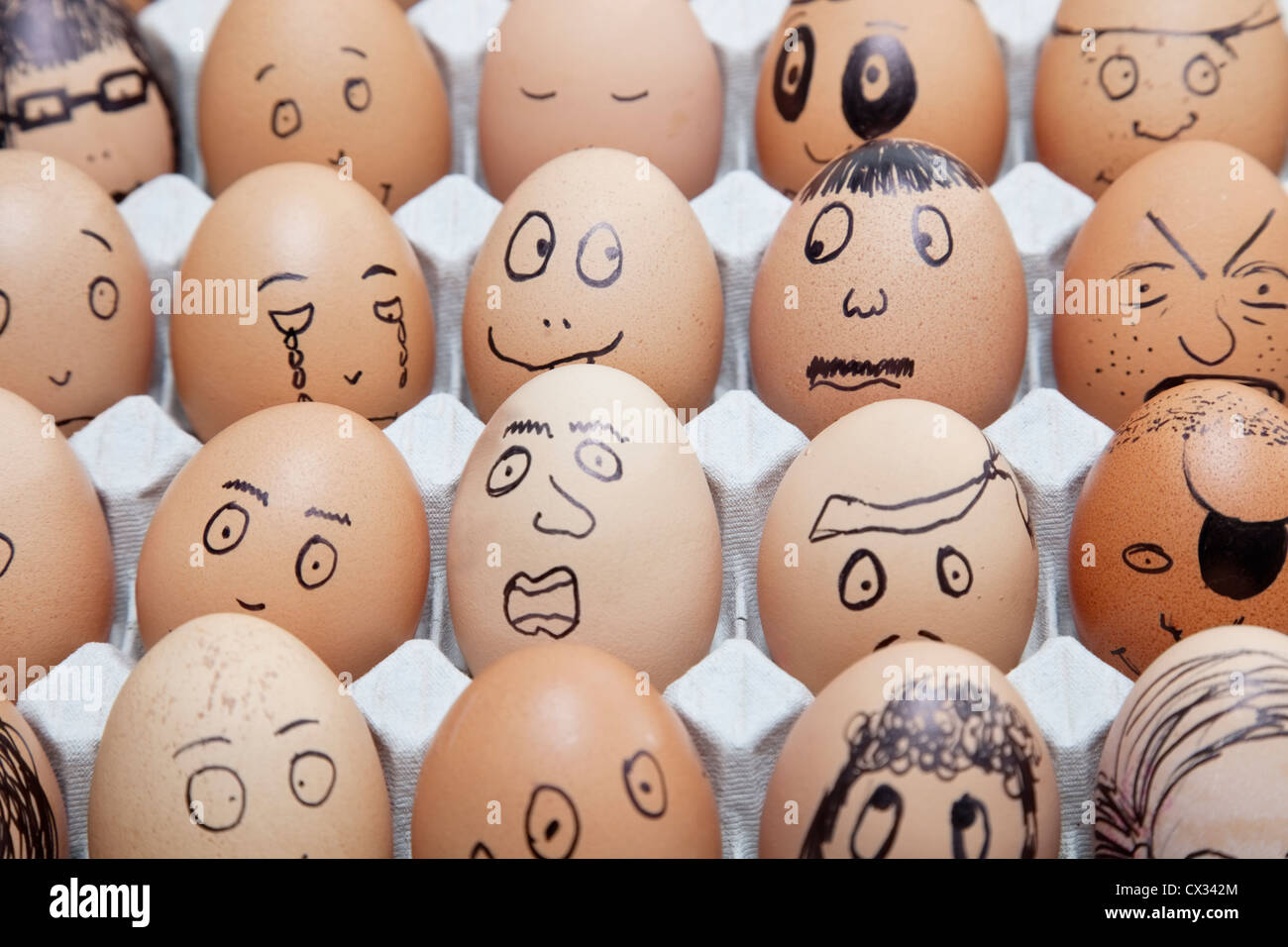 Funny faces on painted on brown eggs arranged in carton Stock Photo