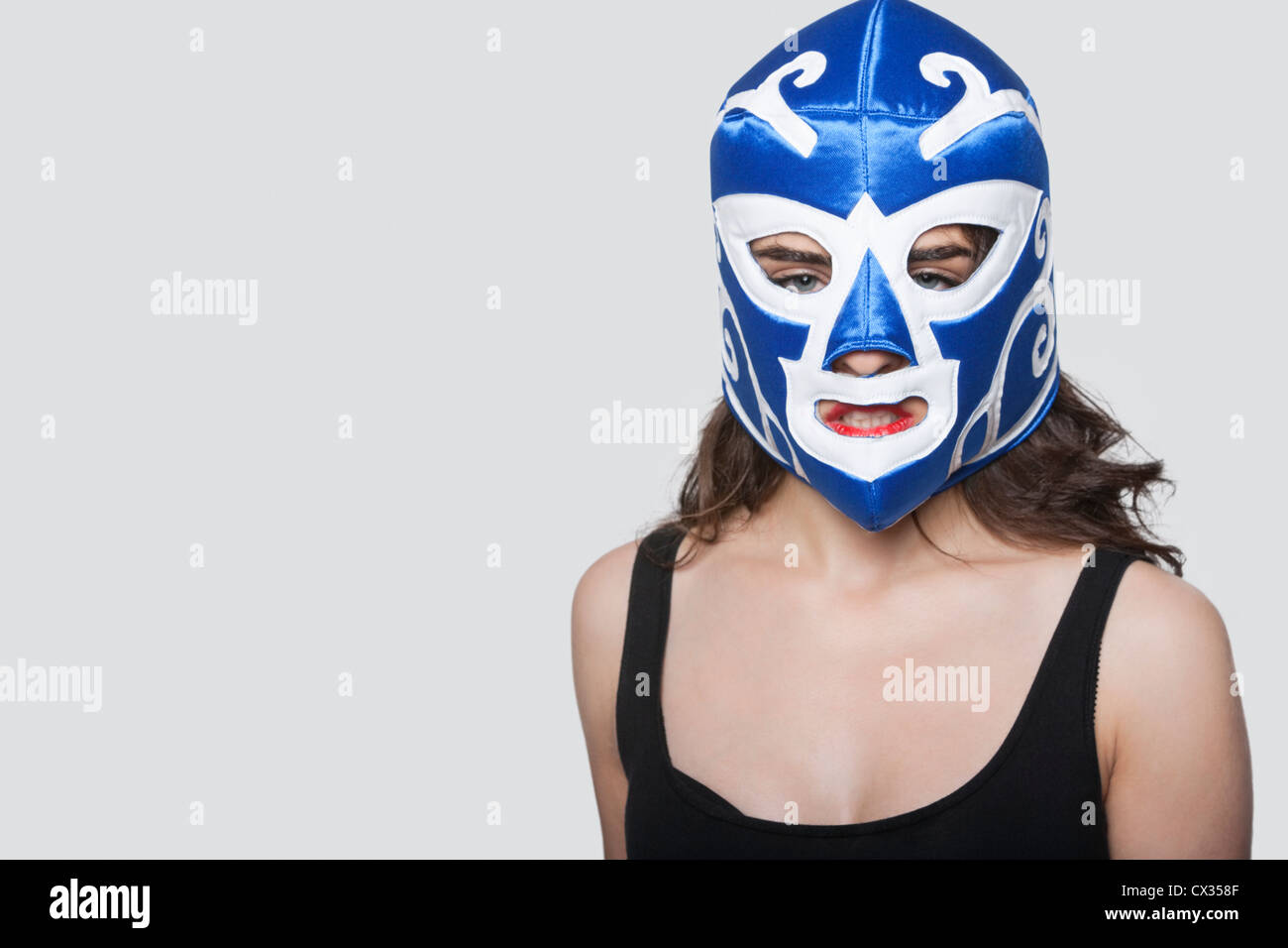 Portrait of a young woman wearing wrestling mask over gray background Stock Photo