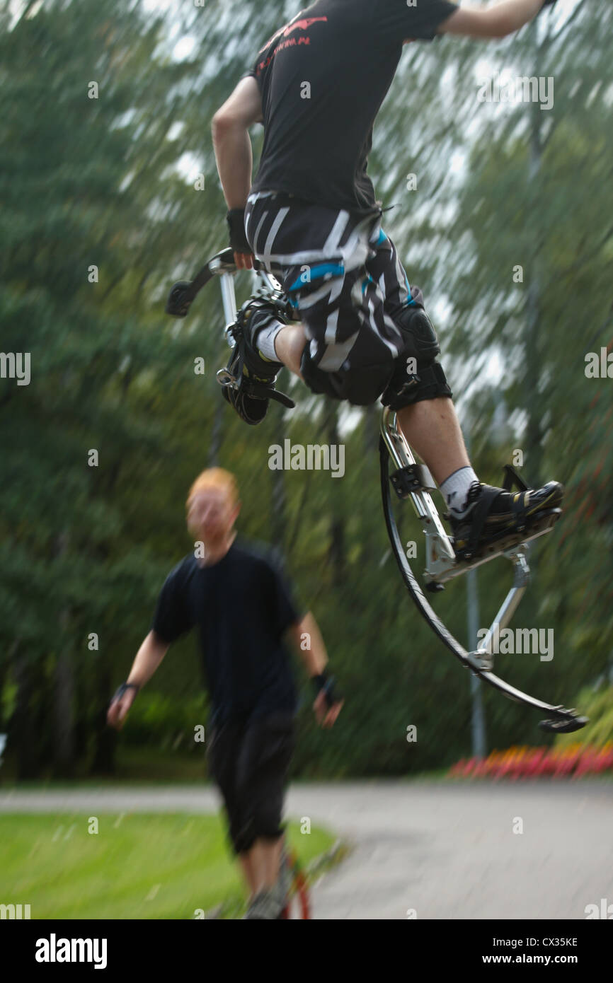 Young people wearing jumping stilts exercising in the park Stock Photo Alamy