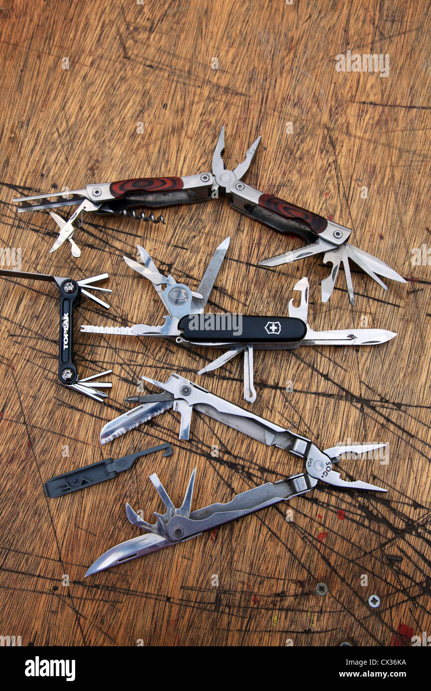 Penknives on a heavily worn table with their blades pulled out. Stock Photo