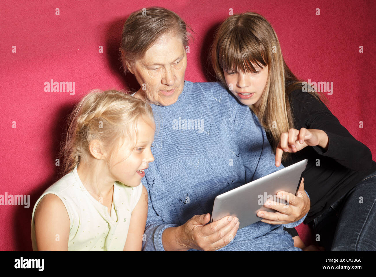 two sisters shows photos to his grandmother on the Tablet PC Stock Photo